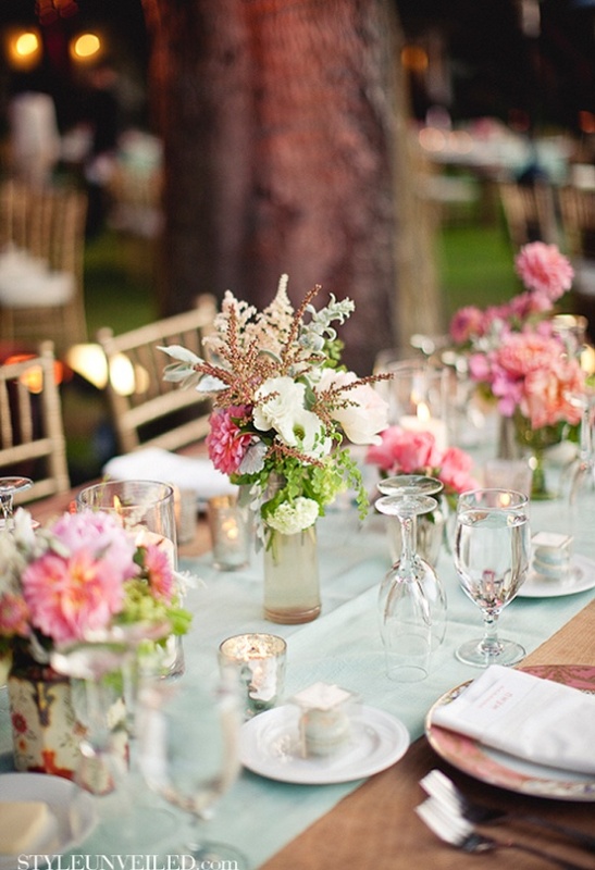 A light mint green wedding table runner looks cool and fresh with bright pink blooms that are centerpieces