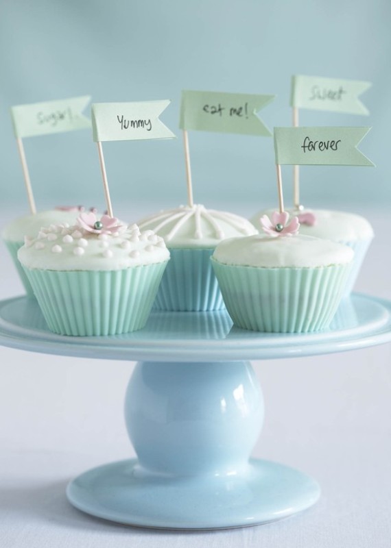 Cute cupcakes with icing, edible beads and flowers in mint green liners and with fun toppers