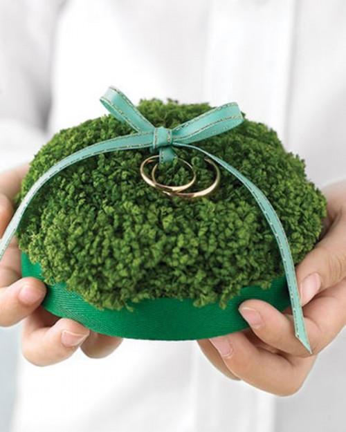 a yarn pillow with rings and a green bow, an emerald base