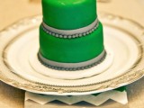 an emerald mini cake decorated with grey beads and ribbons and sugar blooms on top