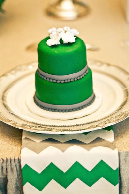 An emerald mini cake decorated with grey beads and ribbons and sugar blooms on top