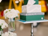 a white and emerald wedding cake with geometric patterns and a large bow