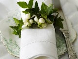 a napkin ring of greenery and white berries is a fresh and cute idea for any tablescape