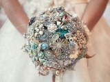 a bright and shiny vintage brooch wedding bouquet with feathers is a stylish and cool idea to DIY
