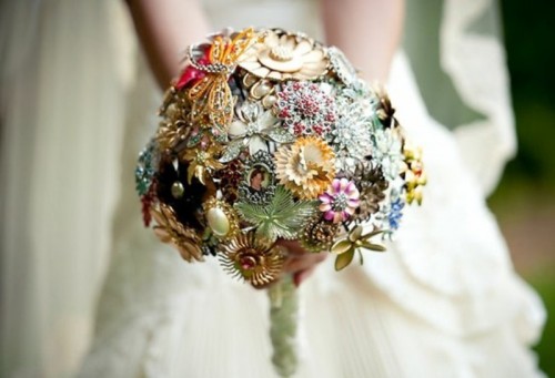 a colorful brooch and button wedding bouquet with a neutral wrap is a bright and bold idea