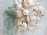 a beach or coastal wedding bouquet fully made of seashells and aqua-colored ribbons with a bow