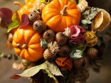 a rustic fall wedding bouquet with pumpkins, leaves, acorns and even fruit plus dried foliage