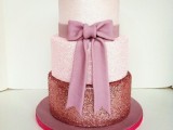 a cute pink glitter wedding cake with a lighter and a darker tier, with a large pink sugar bow is wow