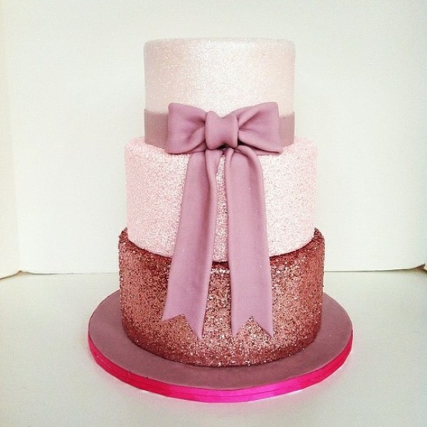 A cute pink glitter wedding cake with a lighter and a darker tier, with a large pink sugar bow is wow