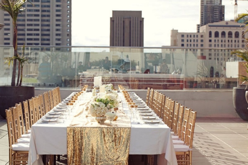 A gold glitter table runner, gold glasses and chairs create a glam look and feel at the reception