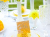 a bright spring wedding tablescape with white and yellow plates, yellow blooms in white vases and neutral cutlery is fun and cool