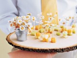 mini fruit skewers topped with fresh blooms and served on a wood slice are a lovely and cool wedding dessert