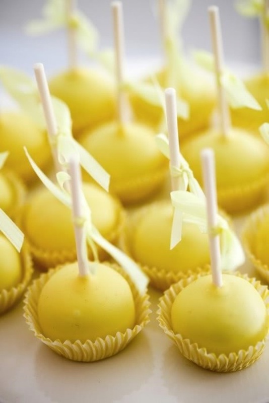 Bold yellow cake pops with bows will be nice wedding favors or sweets for the dessert table