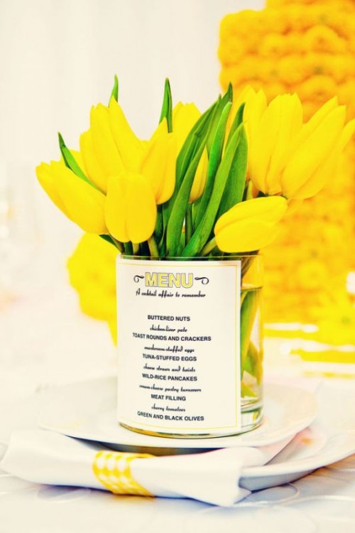 a bold wedding centerpiece of yellow tulips with a menu printed on the vase is a very cool and bold idea