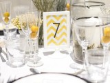 a bold wedding tablescape with billy balls, a bright table number and yellow menus, neutral linens and plates