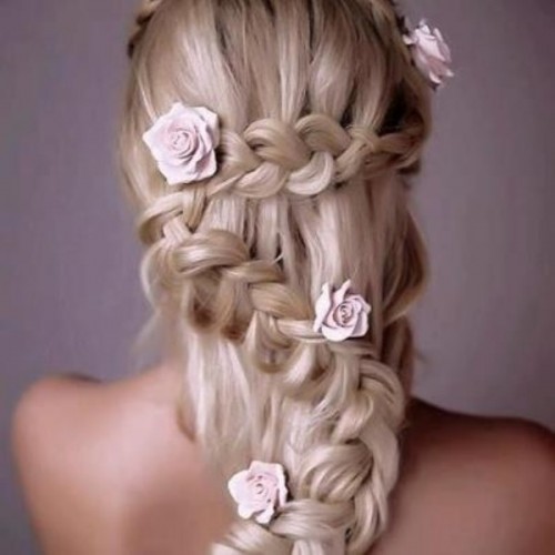 a unique half updo with several braids and fabric blooms integrated to make it more romantic