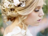 a messy updo with a braided halo plus pink roses and baby’s breath for a romantic and relaxed bridal look