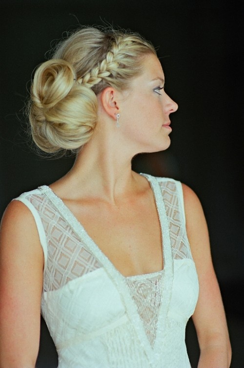 an updo with a braided halo and a large dimensional low bun plus a messy bump