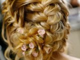 an updo that consists of several braids and is spruced up with fresh blooms