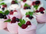 pink and white mini pavlovas topped with fresh berries and greenery