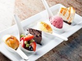 sweet mini desserts on spoons – ice cream, fruits with chocolate, cheesecakes and brownies with chocolate sauce
