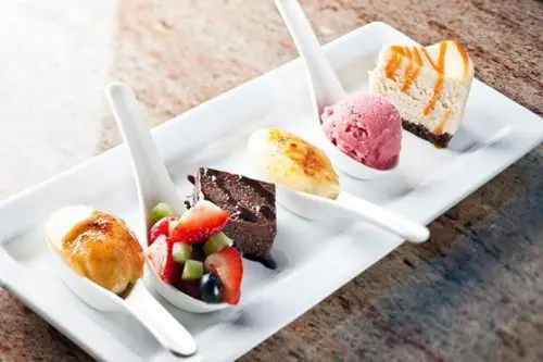 sweet mini desserts on spoons - ice cream, fruits with chocolate, cheesecakes and brownies with chocolate sauce