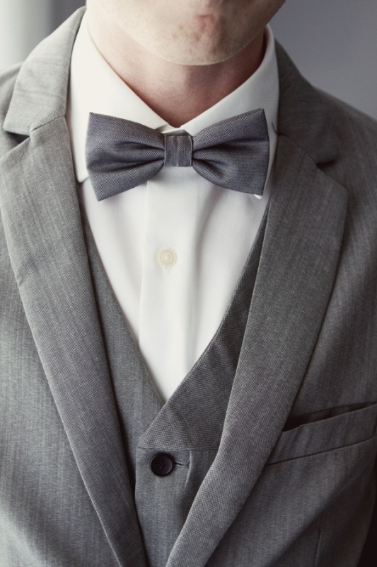 A stylish three piece grey suit, a white shirt and a bow tie compose a timeless groom's look
