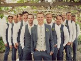 a groom wearing a grey suit and a grey tie and groomsmen wearing grey pants, vests and white shirts