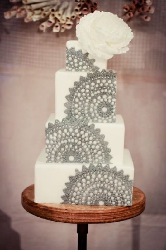 A white square wedding cake decorated with grey lace is a chic and bold dessert to try