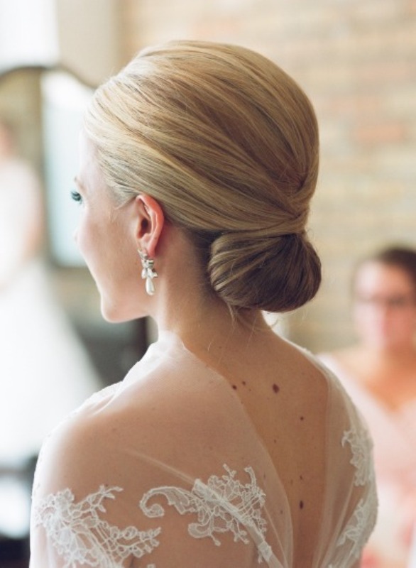 A sleek minimalist wedding twisted low bun with a sleek volume on top is a stylish option for many bridal looks