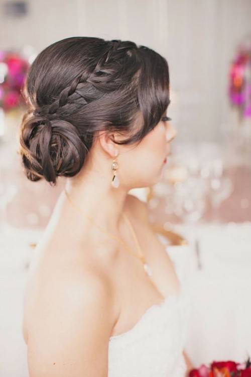 a low wedding updo with a braided halo, a fringe and a low bun is a stylish idea for a refined and chic bride