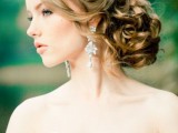 a refined and very chic low wavy wedding updo with no volume on top and some locks down is a fit for a formal wedding