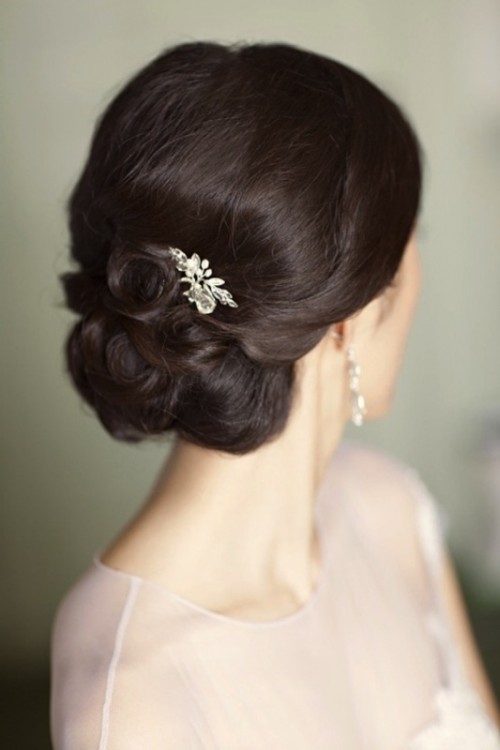 an elegant and laconic wedding updo with a sleek and shiny volume on top and some curls plus an embellished hairpiece is a lovely and bold option to rock