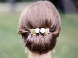 a modern low twisted updo with volume on top and an elegant gold and lace hairpiece for a stylish bride