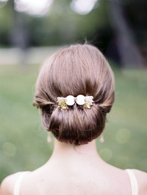 a modern low twisted updo with volume on top and an elegant gold and lace hairpiece for a stylish bride