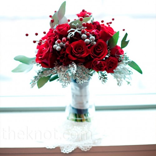 a traditional Christmas wedding bouquet of red roses, berries, pale millet and greenery looks bold and spectacular