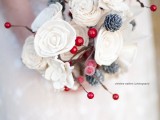 a pretty Christmas wedding bouquet of white blooms, berries, frostted berries and pinecones is a nice fit for a Christmas bride