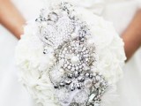 a white rose wedding bouquet with vintage brooches inserted in the middle is a very chic and exquisite idea for a Christmas bride