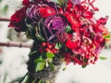 a jewel-tone wedding bouquet made of red, purple, orange blooms and cabbage, of berries and leaves for a color-loving Christmas bride