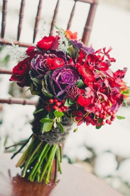 a jewel-tone wedding bouquet made of red, purple, orange blooms and cabbage, of berries and leaves for a color-loving Christmas bride
