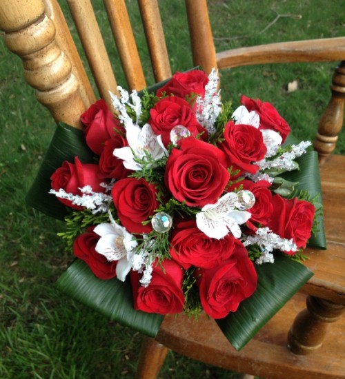 a bold Christmas wedding bouquet of red and white blooms, leaves and some rhinestones to sparkle
