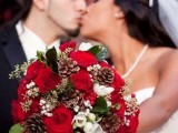 a contrasting Christmas wedding bouquet of red, white blooms, leaves and pinecones and some berries is a bold idea for winter