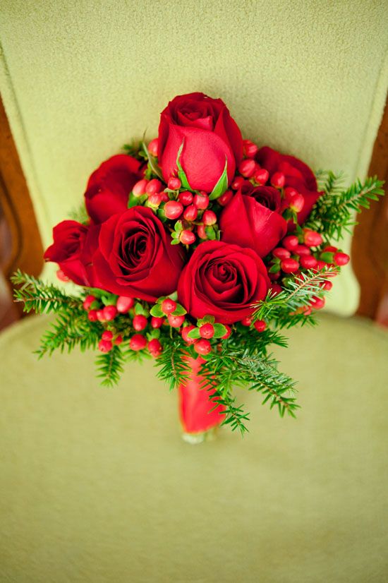 A bold Christmas wedding bouquet of red roses, fir branches and red berries is a bright and cool idea to rock