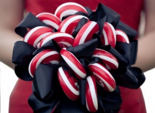 A non traditional Christmas wedding bouquet of candy canes and black bows is a bold and cool way to go