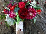a bold Christmas wedding bouquet of red, fuchsia and burgundy blooms, usual and pale greenery