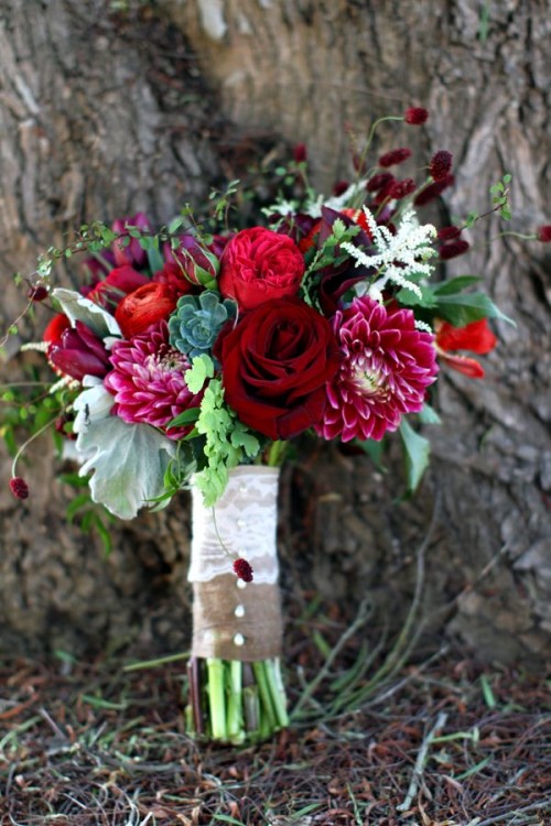 a bold Christmas wedding bouquet of red, fuchsia and burgundy blooms, usual and pale greenery