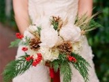 a chic Christmas wedding bouquet of white blooms, pinecones, berries, greenery and some twigs is a beautiful idea