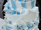 a blue and white Christmas wedding cake decorated with stripes, blooms  and large white bows looks frozen and very pretty