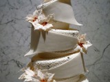 a refined white Christmas wedding cake of sculptural tiers, patterned tiers and with sugar blooms and feathers is a statement