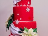 a red Christmas wedding cake with textural tiers, white ribbons and snowflakes plus sugar poinsettia blooms for a traditional Christmas feel